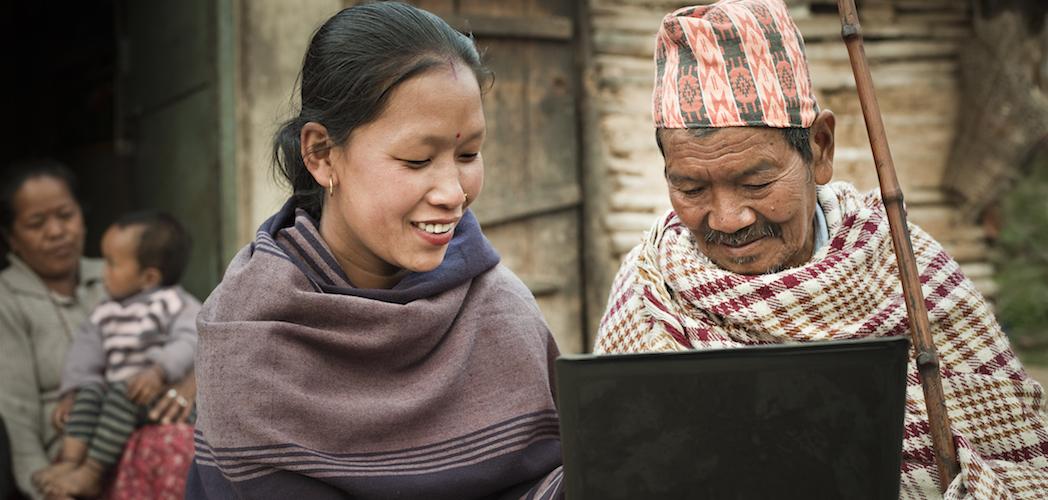 Rural Asian young woman showing laptop to a senior man.