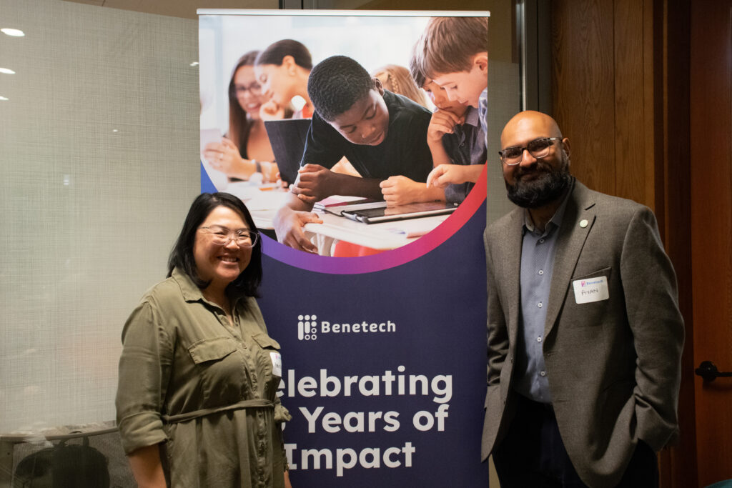 Wendy Wong and Ayan Kishore, stand and smile in front of a Benetech 25th anniversary banner.