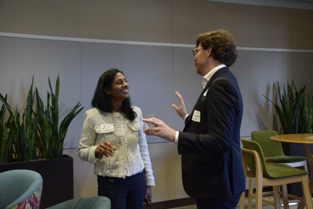 Pallavi Gondipalli and Christopher Lohse converse while smiling and holding drinks.