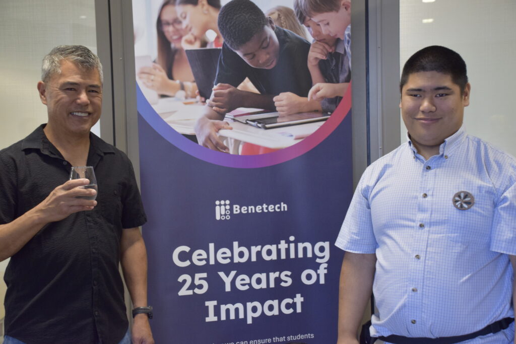 Kevin Leong and guest pose in front of Benetech Celebration banner