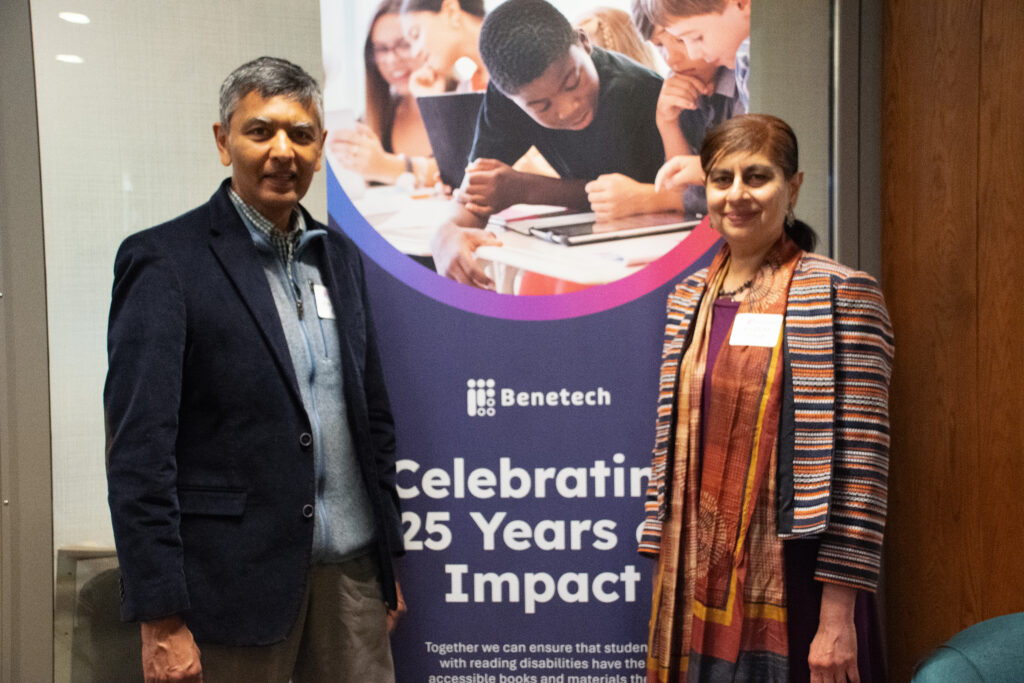 Board Member Radhika Shah and guest pose beside a Benetech banner celebrating 25 years of impact.