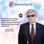 Promotional graphic for Benetech featuring John R. Todd, a Bookshare user. John is a white older man wearing a navy suit, red tie, and dark sunglasses, holding a white mobility cane. The Benetech logo appears at the top. Text on the image reads: “These veterans are building a life after service. They need access,” John says. “Bookshare can change their lives the way it changed mine.” — John R. Todd, Bookshare User. The background is a soft watercolor blend of blue, purple, and pink.